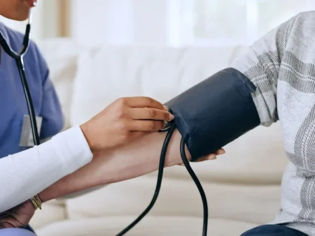 Healthcare worker checks a patient's blood pressure with an arm cuff and stethoscope indoors