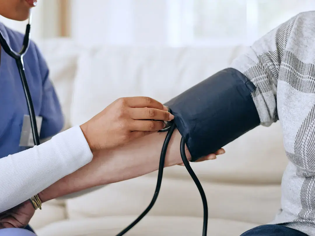 How Can Everyday Lifestyle Habits Help Lower Blood Pressure Naturally? Healthcare worker checks a patient's blood pressure with an arm cuff and stethoscope indoors
