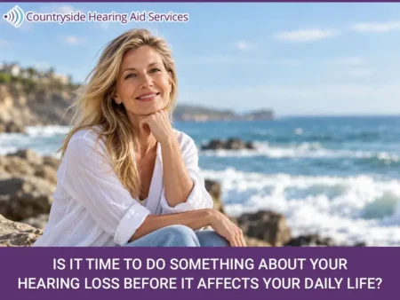 Smiling woman sitting by the ocean with text about addressing hearing loss from Countryside Hearing Aid Services